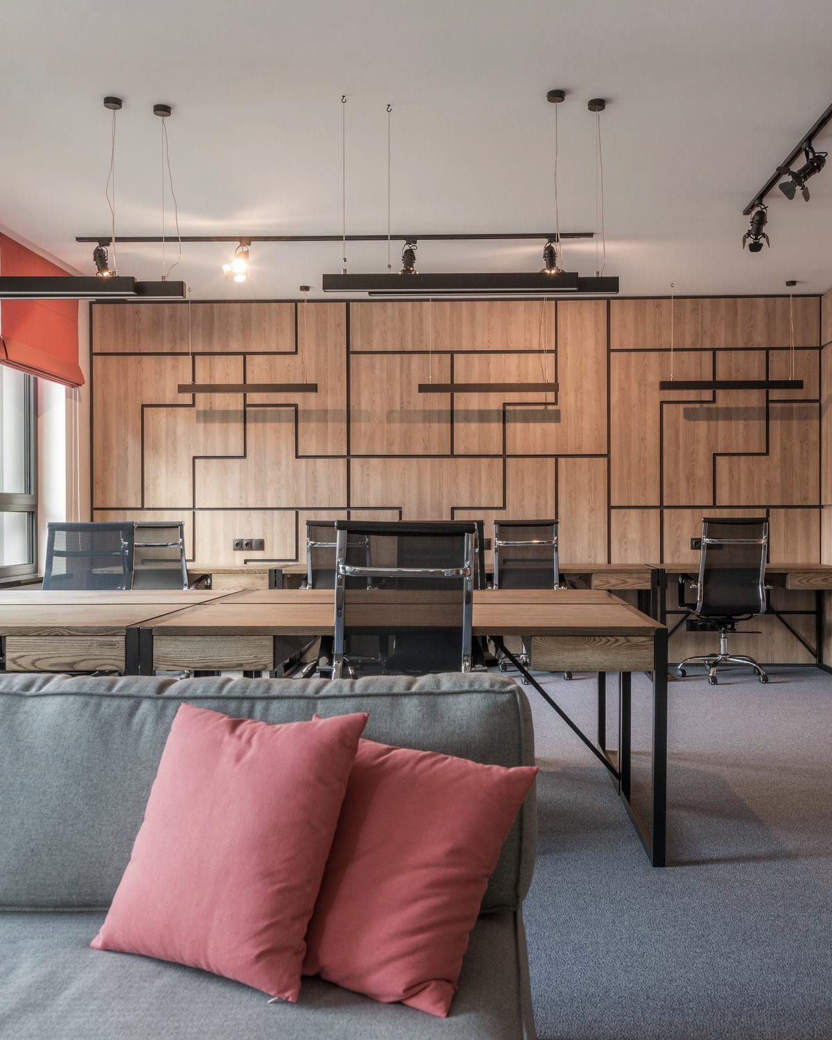 A small studio: one shared desk island against a panelled wall, under daylight.